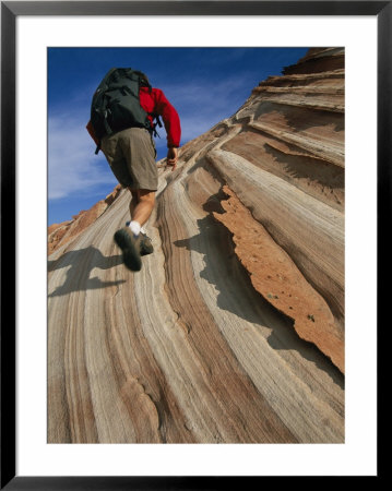 A Hiker On A Sandstone Cliff Patterned By Sedimentary Layers by Bill Hatcher Pricing Limited Edition Print image