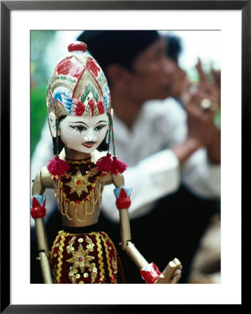 Traditional Puppet With Vendor In Background, Jakarta, Indonesia by Nicholas Pavloff Pricing Limited Edition Print image