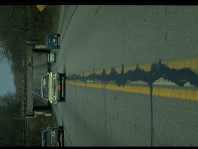 Car Straddling Double Yellow Line In Dangerous Decaying Highway With Tar Patches by Ralph Crane Pricing Limited Edition Print image