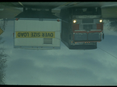 Tractor Trailers Passing In Different Directions On 2-Lane Highway In Rain by Ralph Crane Pricing Limited Edition Print image