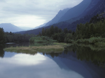 Calm Lake Reflecting Mountains, Trees And An Overcast Sky by Stephen Sharnoff Pricing Limited Edition Print image