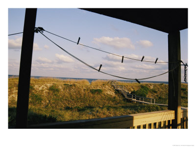 A Quiet Stretch Of Ocean Front Framed By The Wooden Porch Of A Beach House by Stephen St. John Pricing Limited Edition Print image