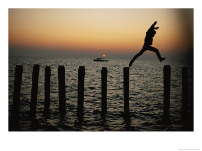 Bo Hoppin Leaps Between Pilings In The Chesapeake Bay Off Great Fox Island, Virginia by Robert Madden Pricing Limited Edition Print image