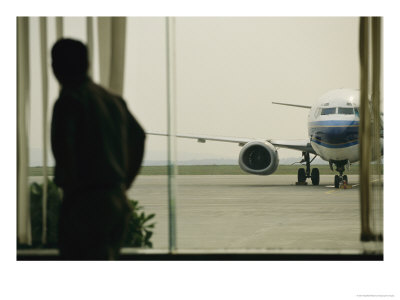 Man At A Chinese Airport Walks Past An Airplane Parked Outside by Eightfish Pricing Limited Edition Print image
