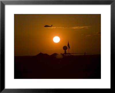 Uh-60 Blackhawk Flies Over Camp Speicher Airfield At Sunset by Stocktrek Images Pricing Limited Edition Print image