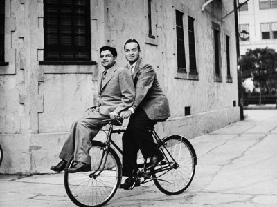 Columnist Sidney Skolsky Riding On Bob Hope's Bicycle From His Dressing Room To The Sound Stage by John Florea Pricing Limited Edition Print image