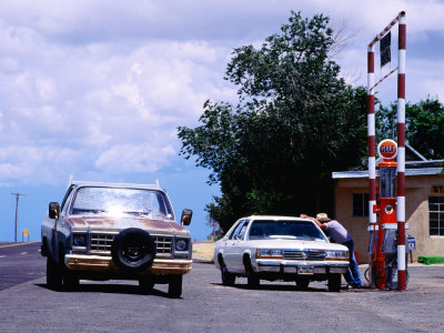 Attendant With Cars At Petrol Station In Stanley, U.S.A. by Curtis Martin Pricing Limited Edition Print image