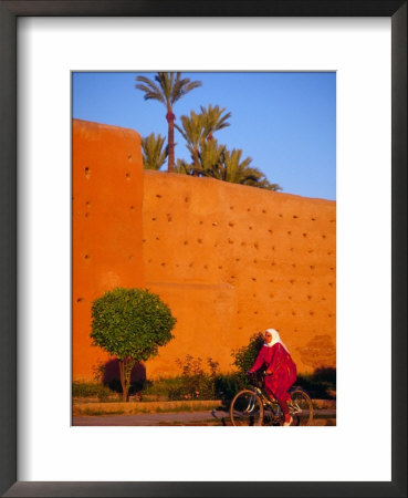Veiled Woman Bicycling Below Red City Walls, Marrakech, Morocco by John & Lisa Merrill Pricing Limited Edition Print image
