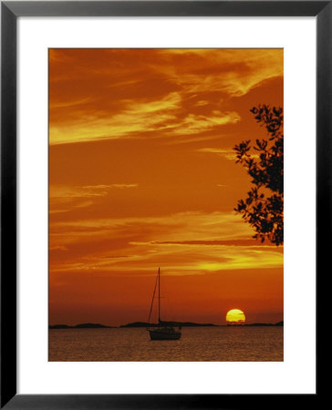 A Sailboat Is Silhouetted By A Brilliant Orange Sunset by Nicole Duplaix Pricing Limited Edition Print image