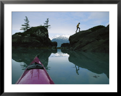 Reflection In Water Of Man Climbing On Large Rocks Near A Sea Kayak by Kate Thompson Pricing Limited Edition Print image