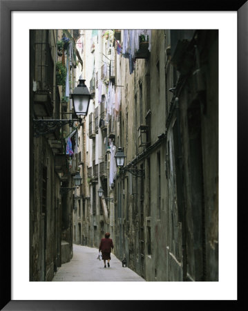 A Woman Walking Along The Narrow Streets Of Bracelona, Spain by Michael Melford Pricing Limited Edition Print image