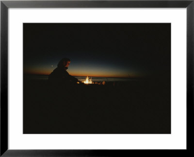 A Woman Tends A Fire On A Beach At Sunset by Todd Gipstein Pricing Limited Edition Print image