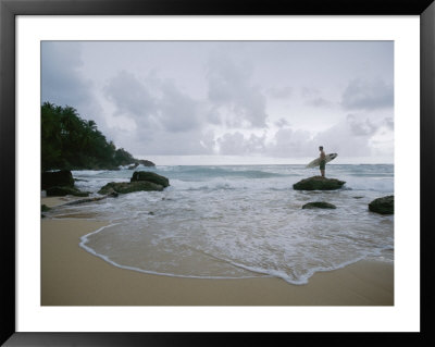 A Man Stands With A Surfboard On A Beach In The Dominican Republic by Stephen Alvarez Pricing Limited Edition Print image