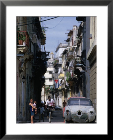 Woman With Baby, Man On Bicycle And Old Car In A Narrow Street Lined With Houses, Havana, Cuba by Rick Gerharter Pricing Limited Edition Print image