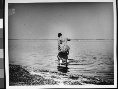 A Fully-Dressed Woman Wading At The Shore Of The Beach In Sag Harbor, Li, Ny by Wallace G. Levison Pricing Limited Edition Print image