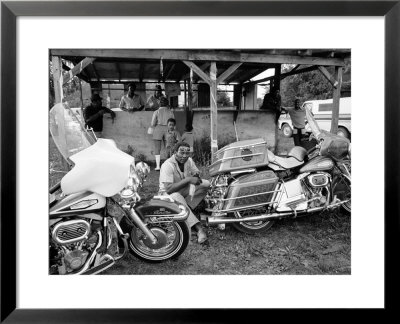 Black Motorcyclist Of The Big Circle Motorcycle Association Sitting Between Harley Davidson Bikes by John Shearer Pricing Limited Edition Print image