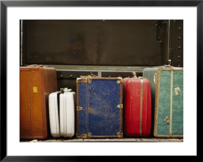 Colorful But Worn Luggage Awaits Travelers In A Train Station by Raul Touzon Pricing Limited Edition Print image