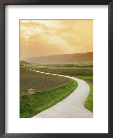 The Golden Sun Glows Through Cloud Cover To Illuminate A Country Road by Richard Nowitz Pricing Limited Edition Print image