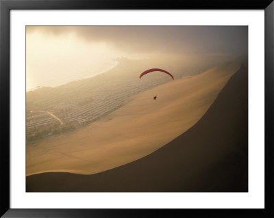 Ocean Gusts Keep A Paraglider Aloft Above Cerro Dragon, A Desert Dune by Joel Sartore Pricing Limited Edition Print image
