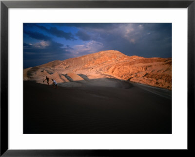 Couple Of Hikers Walking Through Shadows At Dusk, Valle De La Luna, Chile by Aaron Mccoy Pricing Limited Edition Print image