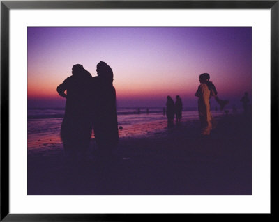 Muslim Women In Saris Watch A Spectacular Sunset From A Beach by Eightfish Pricing Limited Edition Print image