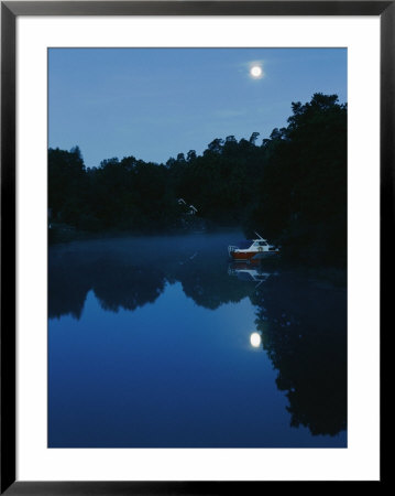 Scenic View Of A Wooded Lake With A Cabin Cruiser And A House Hidden In The Trees by Mattias Klum Pricing Limited Edition Print image