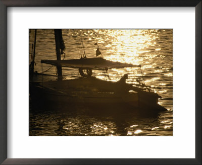 A Silhouetted-Fisherman On A Sailing Boat Looks Out Towards The Setting Sun by Stephen St. John Pricing Limited Edition Print image