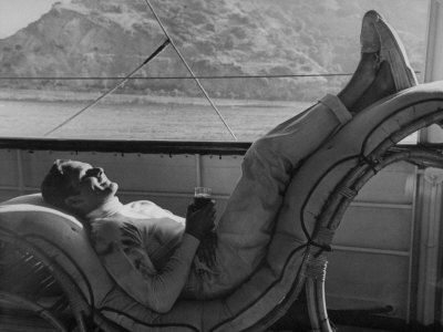 Actor Errol Flynn Holding Drink, Relaxing On His Yacht During A Fishing Trip by Peter Stackpole Pricing Limited Edition Print image