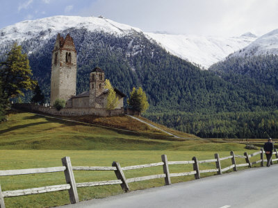 Man Passes A Church With A Forested, Snow-Capped Mountain Backdrop by Thomas J. Abercrombie Pricing Limited Edition Print image
