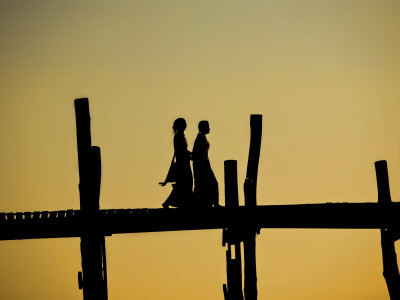 Two Women Walking Across The Ubein Bridge In Mandalay, Burma At Sunset by Scott Stulberg Pricing Limited Edition Print image