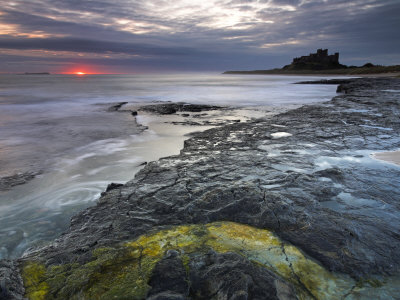 First Glow Of Sunrise Over The Sea Beside Bamburgh Castle, Bamburgh, England, Uk by Adam Burton Pricing Limited Edition Print image