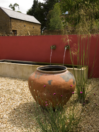 Gravel Courtyard In June With Large Terracotta Container, Red Wall, Water Spouts And Trough by Clive Nichols Pricing Limited Edition Print image