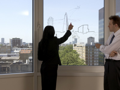 Office Life And Interiors, Employees Discuss Architectural Project Proposal With Sketches On Window by Richard Bryant Pricing Limited Edition Print image