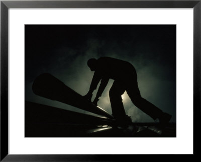 Silhouetted Oil Rig Worker Lifting A Pipe, Wyoming by Lynn Johnson Pricing Limited Edition Print image