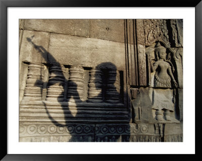 The Silhouetted Shadow Of A Man Holding An Automatic Rifle Is Cast Against A Cambodian Temple Wall by Paul Chesley Pricing Limited Edition Print image