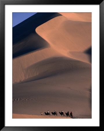 Camel Caravan Traveling Through Taklimakan Desert With Large Sand Dunes In Background, China by Keren Su Pricing Limited Edition Print image