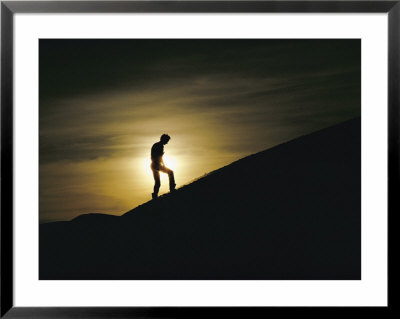 Silhouette Of A Man Walking Up A Dune Against A Cloudy Sun by George F. Mobley Pricing Limited Edition Print image