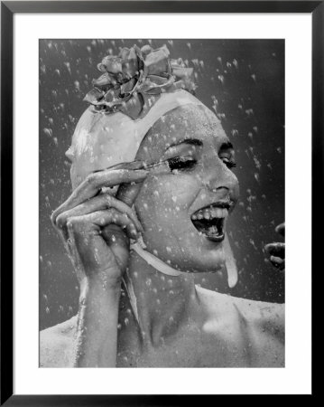 Woman Wearing Flowered Bathing Cap And Applying Mascara As Water Showers Around Her by Gjon Mili Pricing Limited Edition Print image