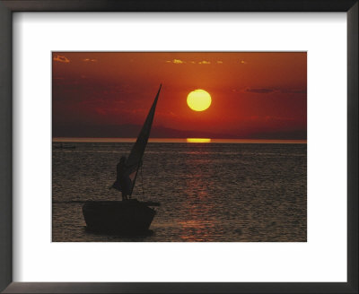 A Windsurfer Comes Near A Small Boat At Sunset by Bill Curtsinger Pricing Limited Edition Print image