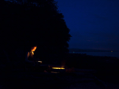 Woman Stares At A Campfire With A Smile by Taylor S. Kennedy Pricing Limited Edition Print image