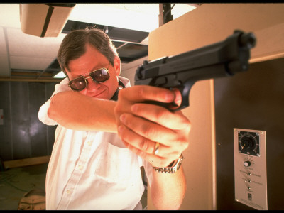 Novelist Tom Clancy With Pistol During Target Practice In His Private Underground Pistol Range by Ted Thai Pricing Limited Edition Print image