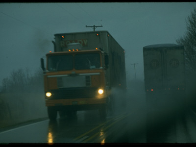 Tractor Trailer Trucks Passing On Highway In Foggy Rain, Dangerous Road Conditions by Ralph Crane Pricing Limited Edition Print image