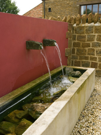 Gravel Courtyard In June With Red Wall, Water Spouts And Trough by Clive Nichols Pricing Limited Edition Print image