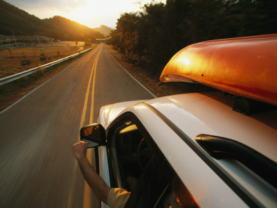 A Car With A Kayak On Top Speeds Down A Two-Lane Highway by Stephen Alvarez Pricing Limited Edition Print image