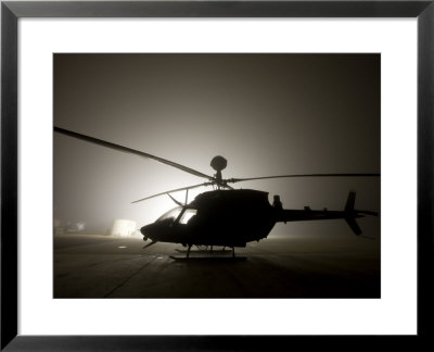 Illumination From The Bright Light Silhouettes Of Oh-58D Kiowa Helicopter During Thick Fog by Stocktrek Images Pricing Limited Edition Print image