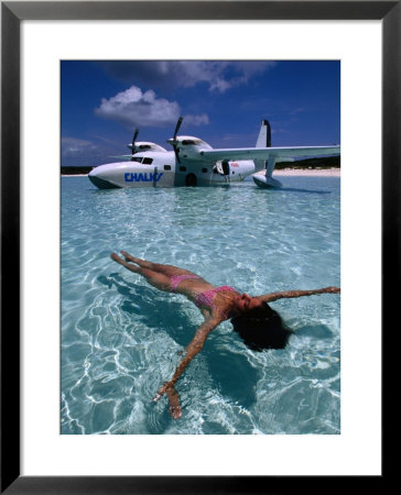 Female Floating In Crystal Waters In Front Of Seaplane, Bahamas by Greg Johnston Pricing Limited Edition Print image