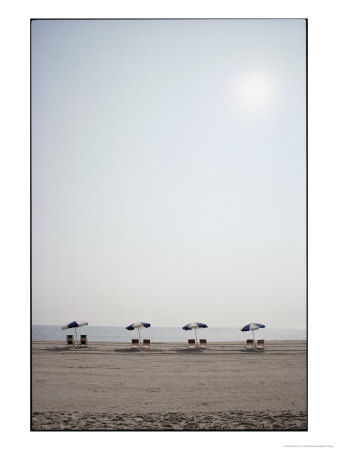 A Row Of Empty Chairs And Umbrellas Await Sun-Worshippers by Stephen St. John Pricing Limited Edition Print image