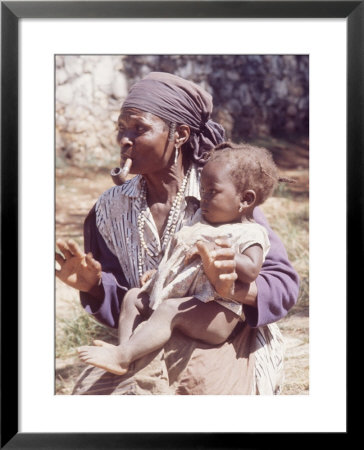 Haitian Woman Smoking A Pipe While Holding A Baby by Lynn Pelham Pricing Limited Edition Print image