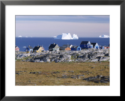 Painted Village Houses In Front Of Icebergs In Disko Bay, West Coast, Greenland by Anthony Waltham Pricing Limited Edition Print image