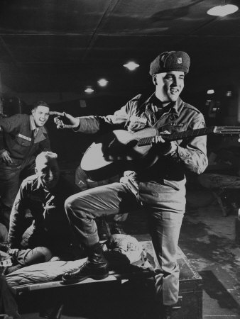 Elvis Presley Sporting Army Winter Cap And Battle Fatigues As He Plays Guitar by Loomis Dean Pricing Limited Edition Print image